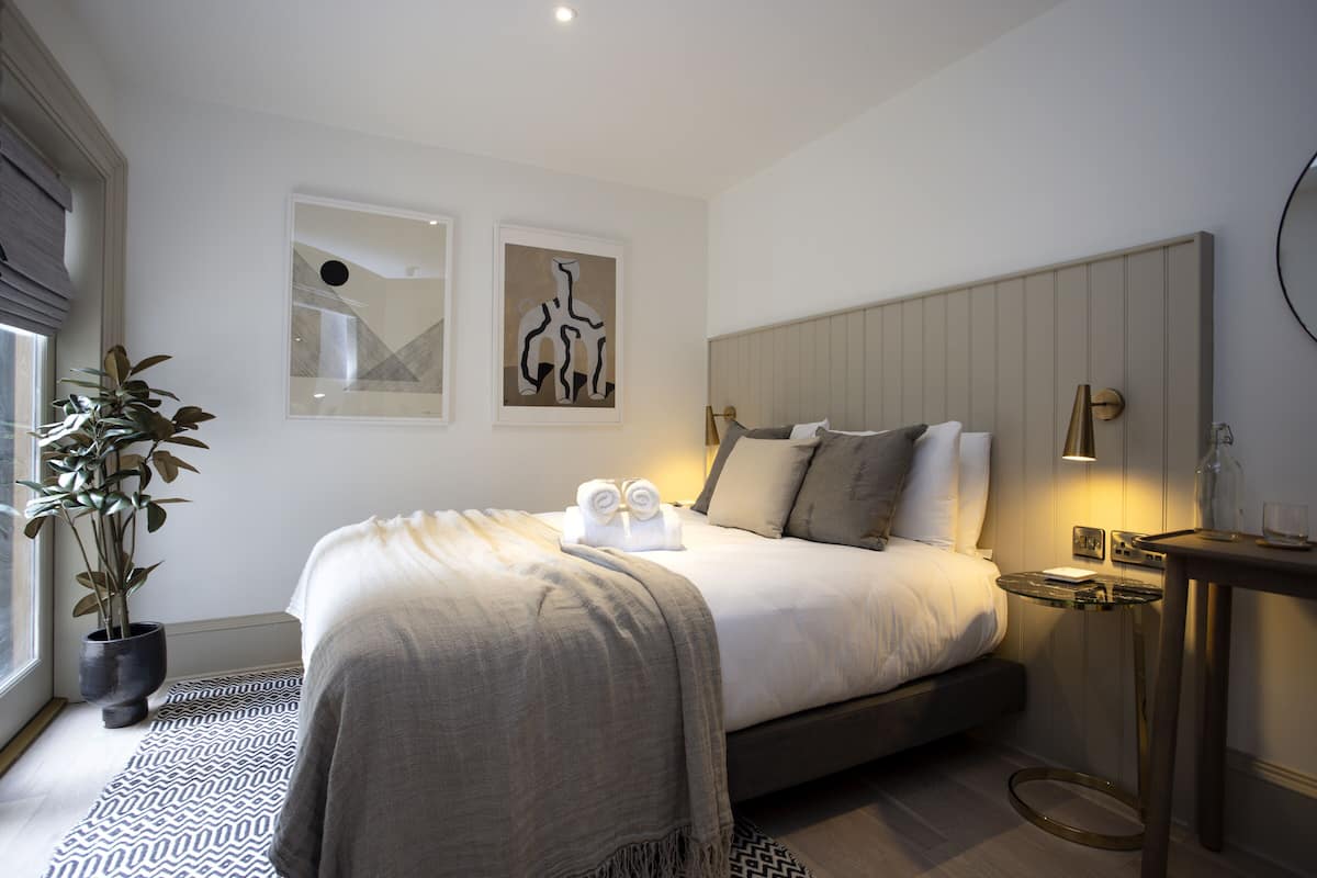 A modern bedroom with a bed, bedside table, lamp, and artwork on the wall.
