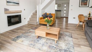 Una sala de estar moderna con chimenea, una escalera y un comedor.