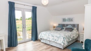 Un dormitorio con cama, una silla, una mesita de noche y vistas al exterior.