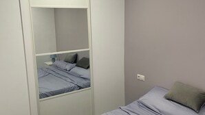 A bedroom with a bed, a wardrobe, and a mirror.