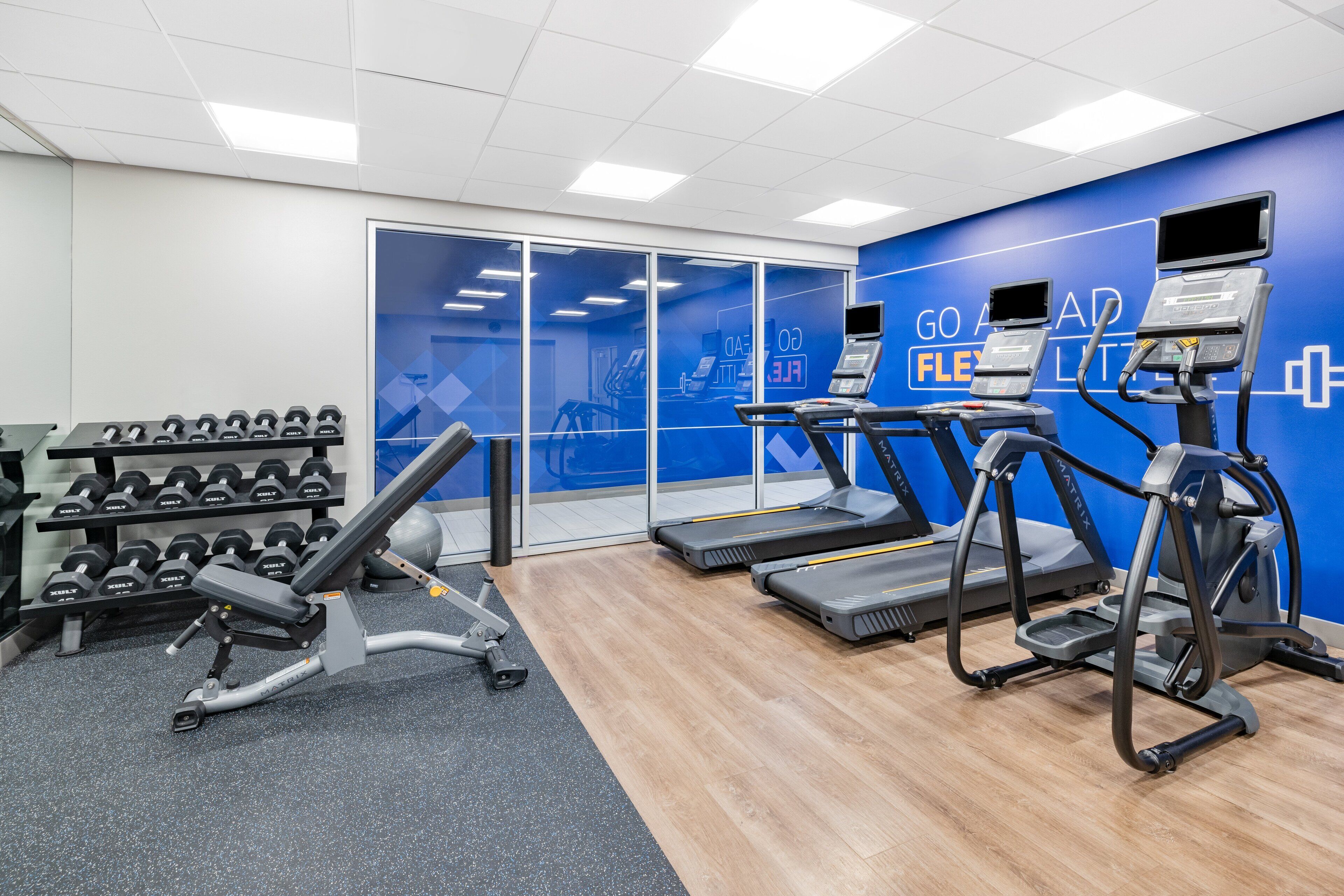 Une salle de sport équipée de tapis de course, d’haltères et d’un banc de musculation.