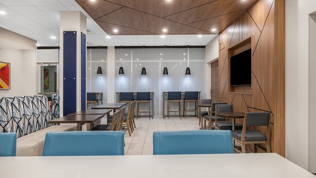 A modern dining area with wooden tables and chairs, a blue cushioned bench, and pendant lighting. - Holiday Inn Express & Suites Nephi by IHG (Nephi)