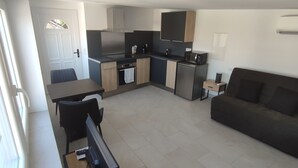 Un espacio habitable compacto con kitchenette, zona de comedor y área de descanso.