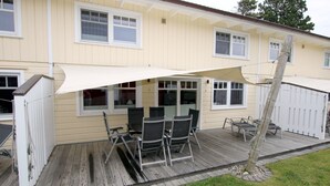 Une maison avec un patio couvert, une clôture blanche et un arbre.