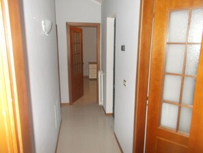 Enter a cozy room with a bed and dresser, accessible through a hallway with a light-colored floor and walls.
