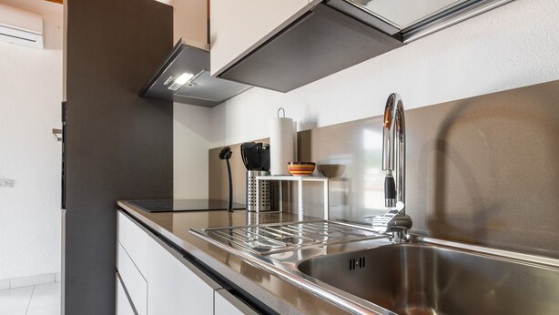 A modern kitchen with a stainless steel sink, a built-in oven, and a range hood. - Holiday Home 'Attico Lussu' with Sea View, Terraces & A/C (Villasimius)
