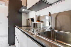 Eine moderne Küche mit Spüle aus Edelstahl, integriertem Backofen und Dunstabzugshaube.