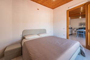 A bedroom with a bed, bedside table, and a wooden ceiling.