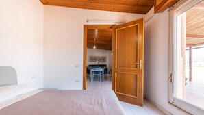 A bedroom with a bed, a wooden door, and a view through a window. - Holiday Home 'Attico Lussu' with Sea View, Terraces & A/C (Villasimius)