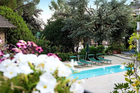 A swimming pool with lounge chairs, surrounded by greenery and trees. - Holiday Home Villa Eden Jacuzzi Pool with Lake View, Wi-Fi & Terrace (Domaso)