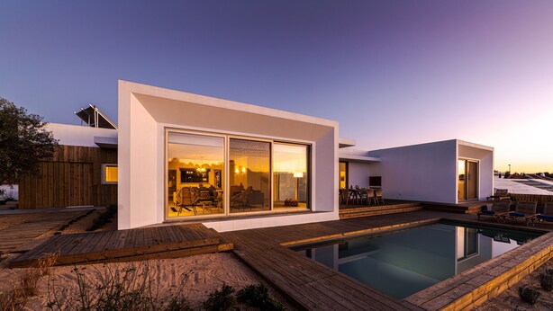 Ein modernes Haus mit Swimmingpool, Holzterrasse und einer Patio.