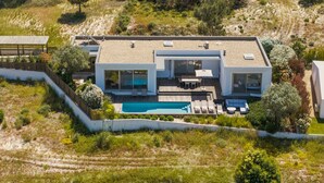 Ein modernes Haus mit Swimmingpool, großen Fenstern und einer Terrasse.