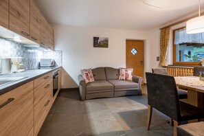 Une cuisine moderne avec des meubles en bois, un coin repas comprenant une table et des chaises, et un canapé agrémenté de coussins décoratifs.
