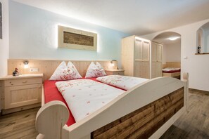 Ein Schlafzimmer mit einem hölzernen Bett, einem Nachttisch, einer Kommode und einem Spiegel.