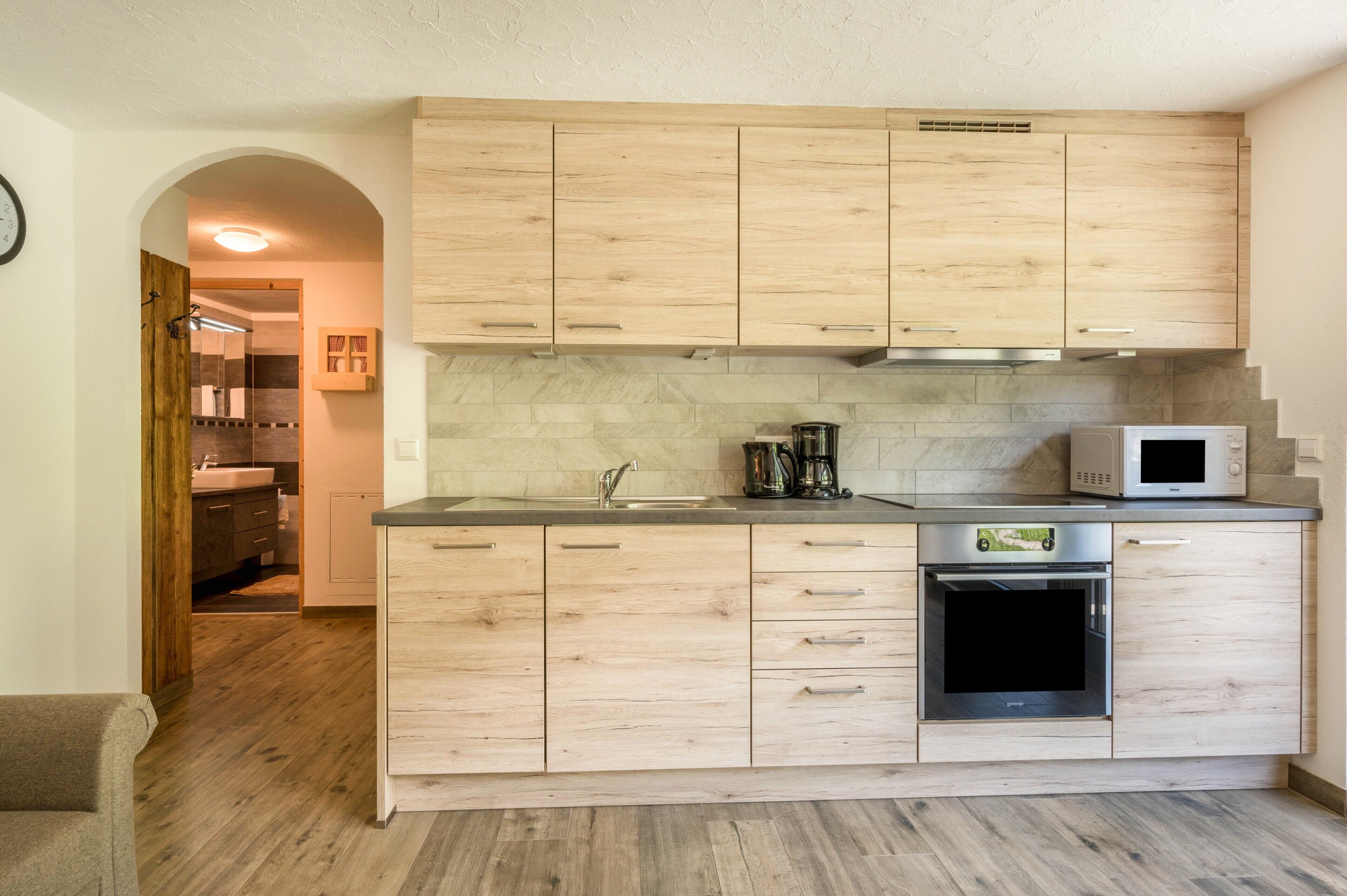 Eine Küche mit Holzausstattung, einer Mikrowelle, einem Backofen und einer Kaffeemaschine.