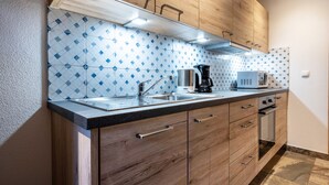 A kitchen with wooden cabinets, a stainless steel sink, a coffee maker, and a microwave. - Apartment "Schwarzenstein" with Shared Whirlpool & Garden (Valle Aurina)