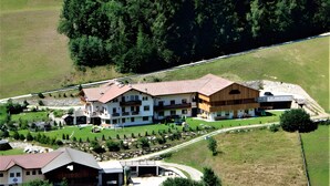 A multi-story building with a sloped roof, surrounded by a well-maintained lawn and trees. - Apartment "Schwarzenstein" with Shared Whirlpool & Garden (Valle Aurina)