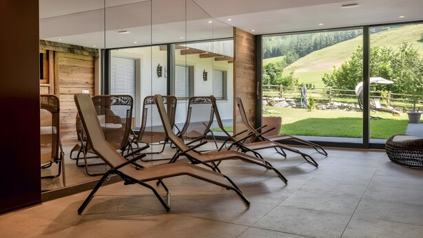 A modern interior with lounge chairs, large windows, and a view of a green landscape. - Holiday Apartment "Weiße Zinne" with Shared Whirlpool & Garden (Valle Aurina)