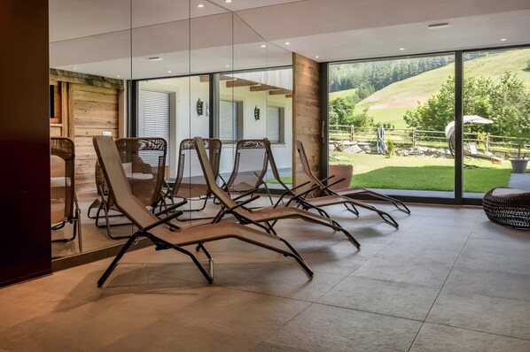 Un interior moderno con sillones, ventanas amplias y vistas a un paisaje verde.