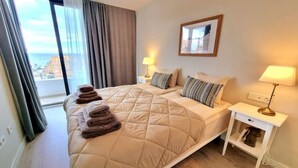 A hotel room with a bed, two bedside tables, a window with curtains, and a framed picture on the wall. - Holiday Home 'Modern Terrassed House Close Beach' with Sea View and Wi-Fi (Málaga)