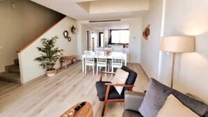 A living room with a staircase, a dining area, and a kitchen in the background. - Holiday Home 'Modern Terrassed House Close Beach' with Sea View and Wi-Fi (Málaga)