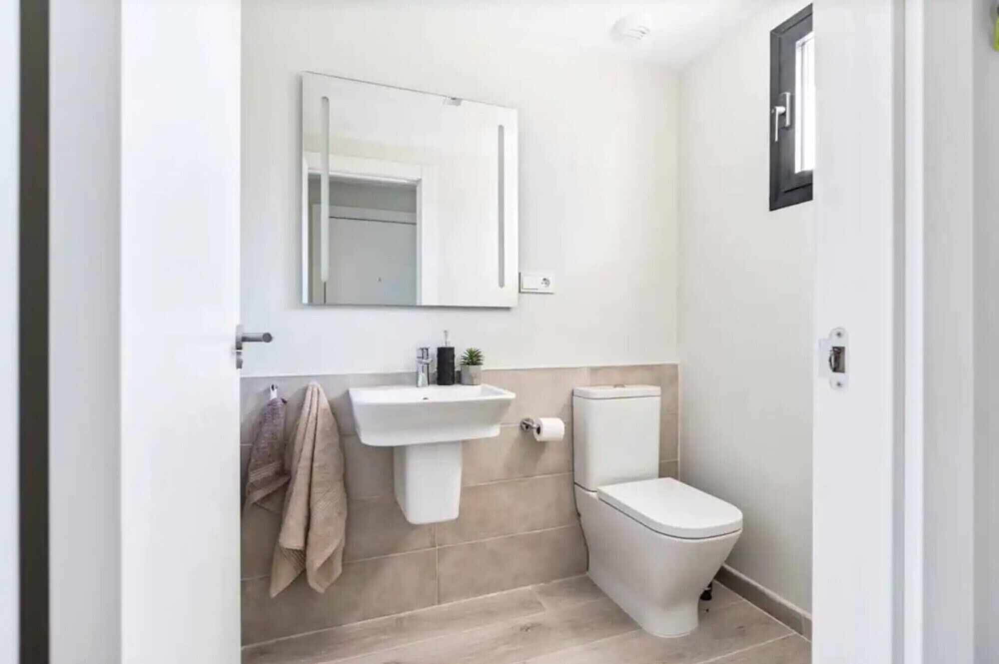 Een badkamer met een wastafel, toilet en spiegel.