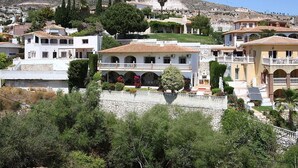 Une ville côtière aux bâtiments de style méditerranéen, notamment une maison à deux étages dotée d’un balcon et d’une cour intérieure.
