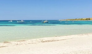Ein Strand mit klarem türkisblauem Wasser und einem Sandufer.