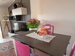 Une table à manger recouverte d’une nappe en dentelle, un vase de fleurs et une chaise rose.