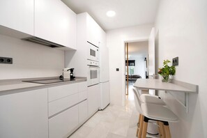 Een moderne keuken met witte kastjes, een inbouwoven en een aanrecht met een koffiezetapparaat.