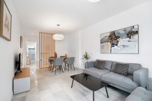Een moderne woonkamer met een bank, salontafel en een eethoek.