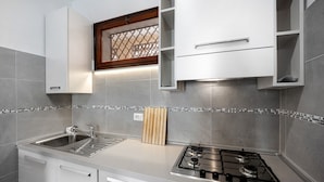 Una cocina moderna con pileta de acero inoxidable, estufa a gas y muebles de cocina blancos.