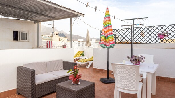 A patio with a sofa, a small table, a chair, an umbrella, and a potted plant. - Apartment Nieves 2 with Sea View, Terrace & Wi-Fi (Nerja)