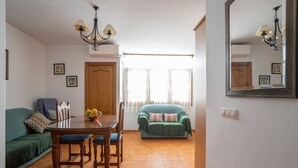 A dining area with a wooden table and chairs, a green sofa, and a mirror on the wall. - Apartment Nieves 2 with Sea View, Terrace & Wi-Fi (Nerja)