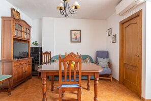 Een eetgedeelte met een houten tafel en stoelen, een televisie en een kast.