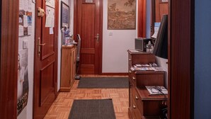 A hallway with wooden floors, a dark rug, wooden cabinets, a television, and a ceiling light.