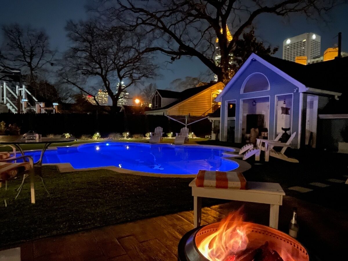 Ein Garten mit Swimmingpool, Feuerstelle und überdachter Sitzgelegenheit.