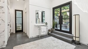 Un baño moderno con un ventanal grande, un lavamanos blanco y un espejo.