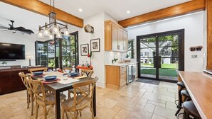 Una cocina moderna con armarios de madera, un comedor con mesa y sillas, y un amplio ventanal con vistas al exterior.