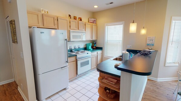 Enjoy cooking in this well-equipped kitchen with a central island, stove, and microwave.