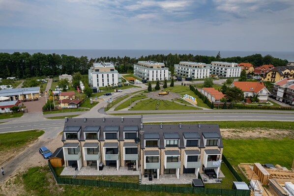 Un quartier résidentiel avec des immeubles d’appartements modernes, un rond-point central et un grand espace ouvert comprenant une aire de jeux.