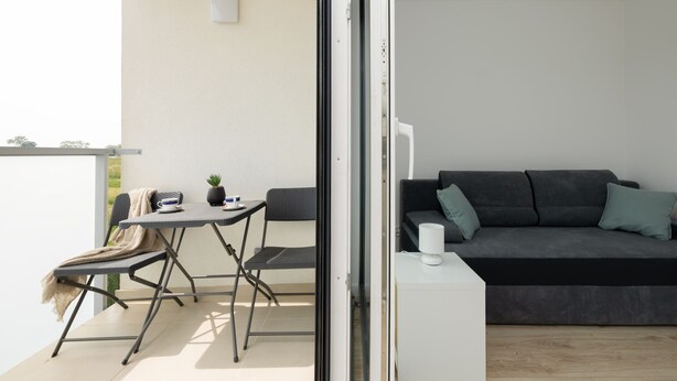 A balcony with a table and chairs, a sofa, and a small white table with a lamp. - Spacious Apartment | 3 Bedrooms, Terrace, 300 m to the Beach (Rewal)