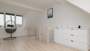 A room with a hanging chair, a white cabinet, and a view through a window. - Spacious Apartment | 3 Bedrooms, Terrace, 300 m to the Beach (Rewal)