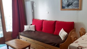 Une pièce chaleureuse avec un canapé en bois, une petite table en bois et un tableau encadré accroché au mur.