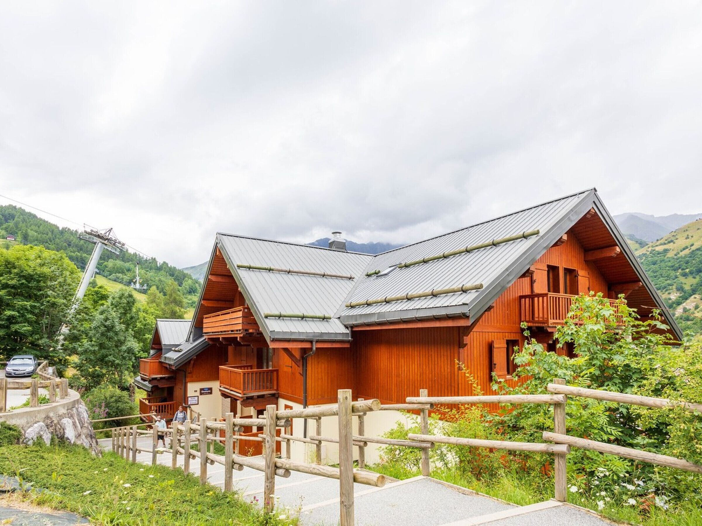 Eine Holzhütte mit geneigtem Dach, einem Holzzaun und einer Bergkulisse.