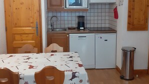 Une cuisine compacte dotée d’armoires en bois, d’un four à micro-ondes, d’une machine à café et d’un lave-vaisselle.