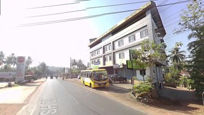 A street with a yellow bus, a building with multiple floors, and a sign for Indian Oil. - Hotel Keerthana Inn (Puttur)