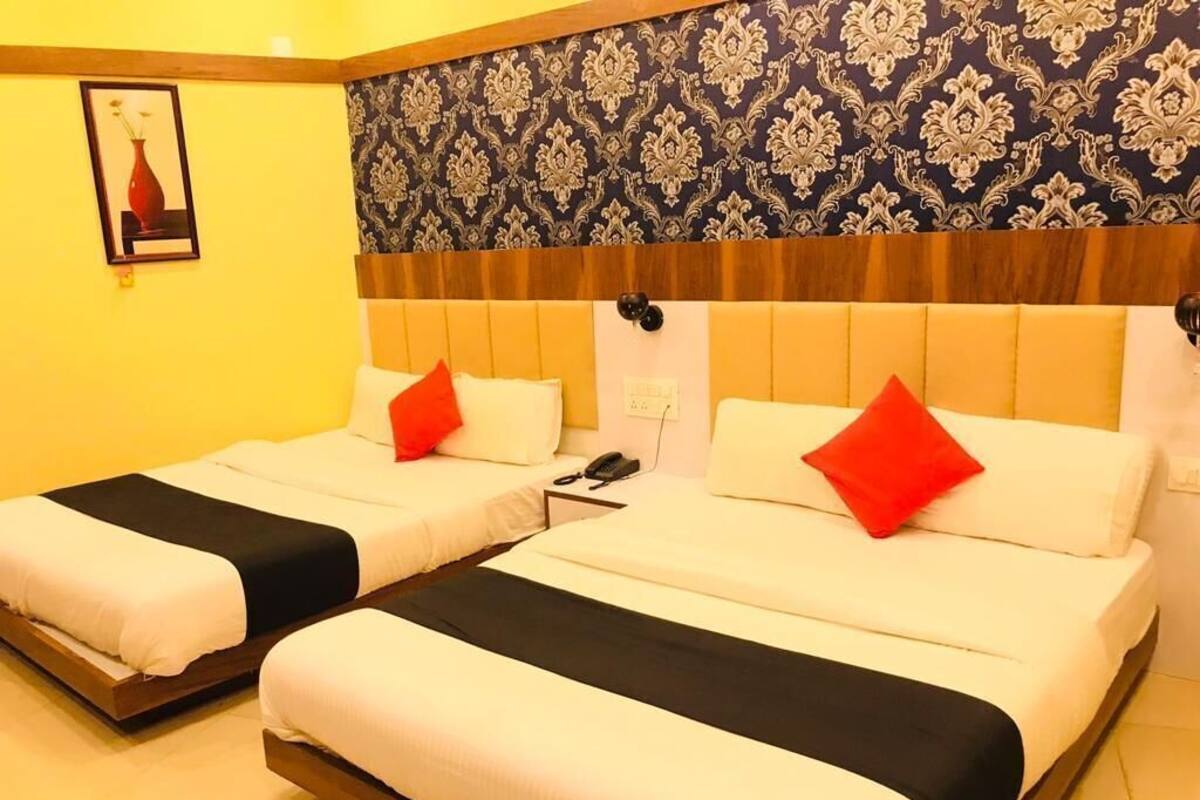 Quarto de hotel com duas camas, papel de parede estampado, um quadro na parede e telefone de apoio.