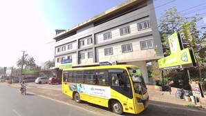 A yellow bus parked in front of a building with multiple windows and a sign that reads "ELTHOR". - Hotel Keerthana Inn (Puttur)