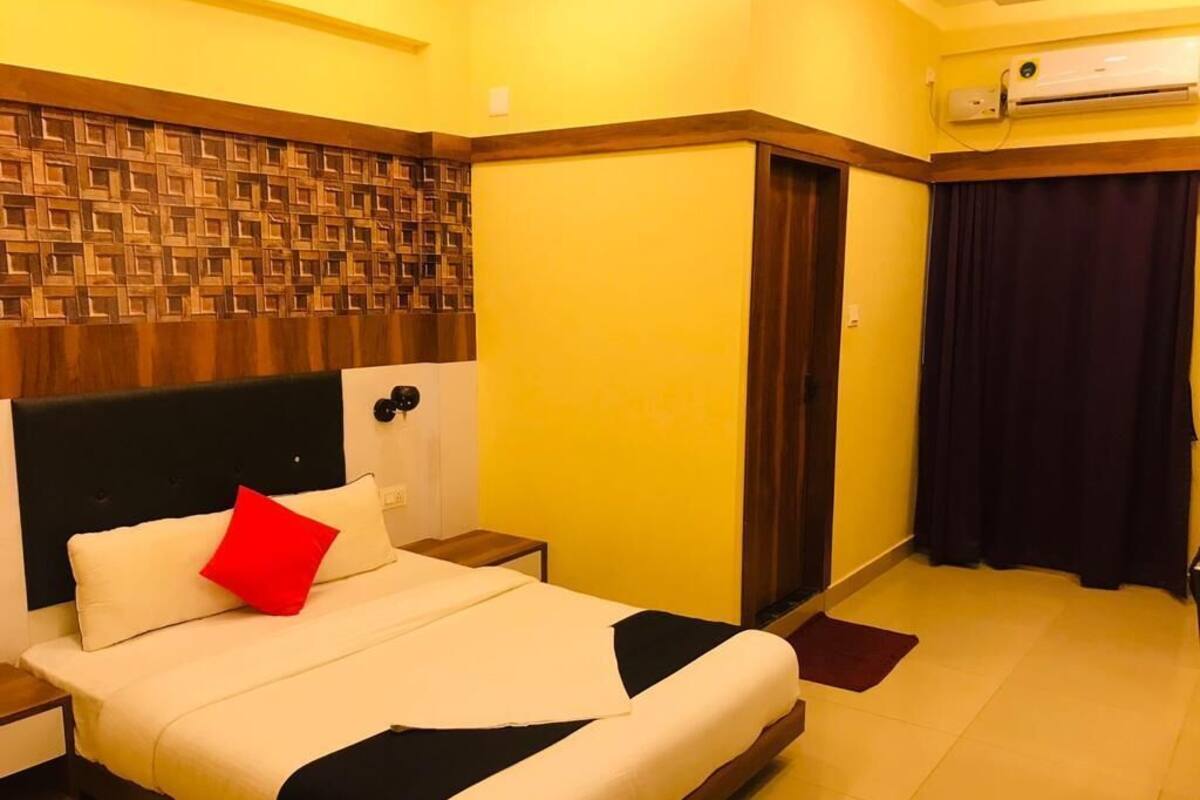 Quarto de hotel com cama, mesa de cabeceira e aparelho de ar condicionado.